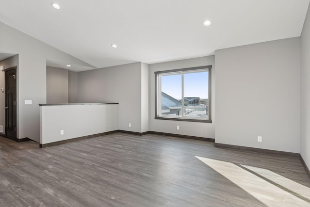 spare room featuring dark hardwood / wood-style flooring and vaulted ceiling