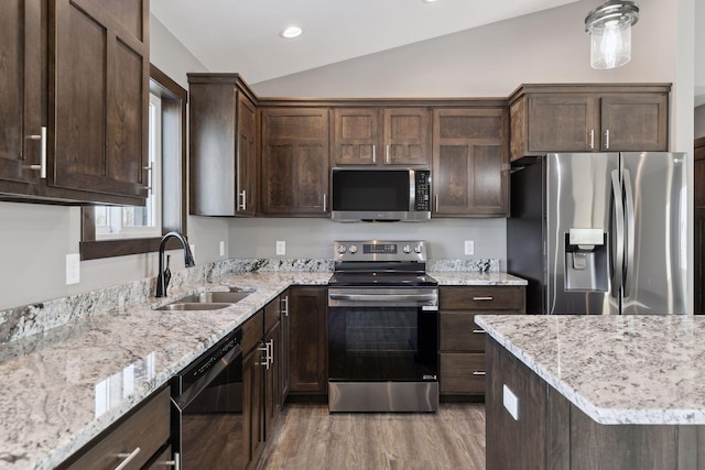 kitchen with vaulted ceiling, sink, light stone counters, stainless steel appliances, and dark brown cabinets