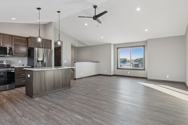 kitchen with a center island, dark brown cabinets, appliances with stainless steel finishes, pendant lighting, and light stone countertops