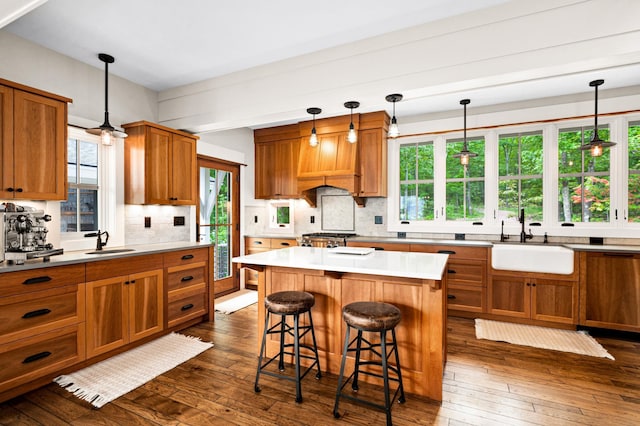 kitchen featuring a center island, sink, decorative light fixtures, and dark hardwood / wood-style flooring