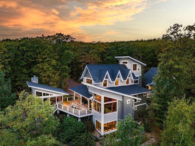 back house at dusk with a balcony and a sunroom