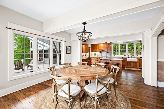 dining space featuring dark wood-type flooring, an inviting chandelier, and sink