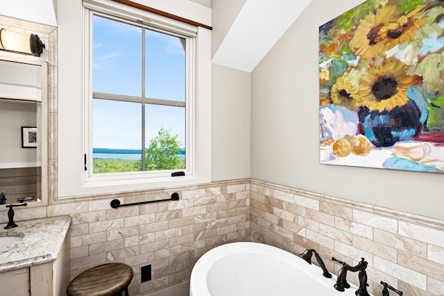 bathroom with a tub to relax in, vaulted ceiling, and vanity