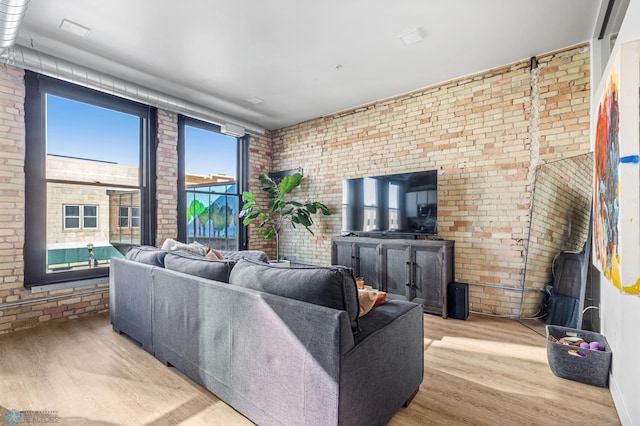 living room featuring light wood-type flooring and brick wall