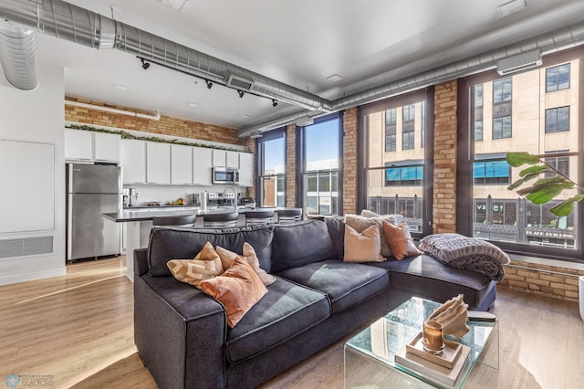 living room with light wood-type flooring and brick wall