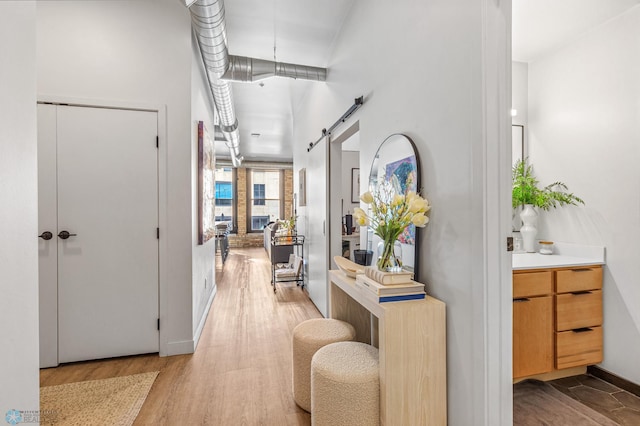 hallway with wood-type flooring and a barn door