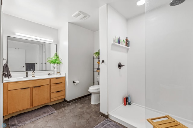 bathroom featuring a shower, tile patterned flooring, vanity, and toilet