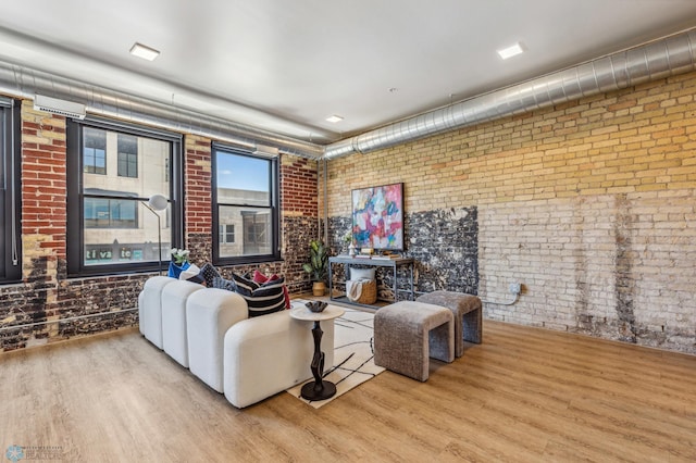 living room featuring light hardwood / wood-style floors and brick wall