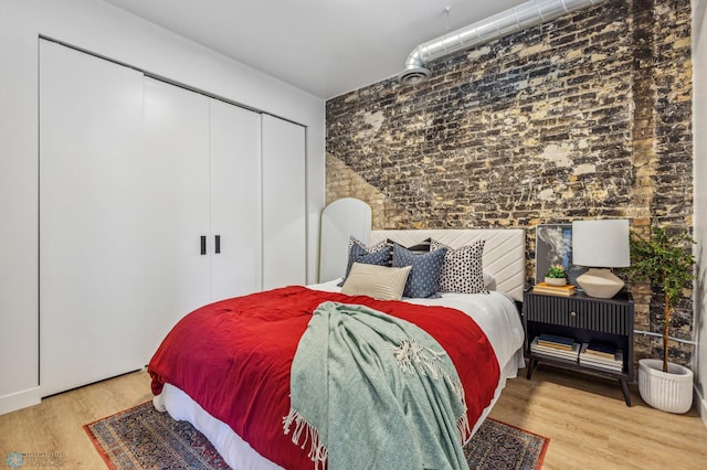 bedroom with hardwood / wood-style floors and brick wall