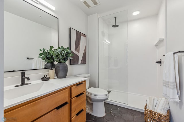 bathroom featuring toilet, a shower, vanity, and tile patterned floors