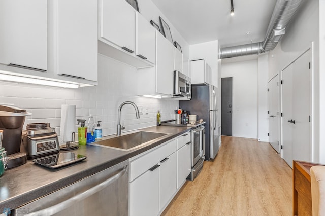 kitchen featuring stainless steel appliances, white cabinetry, light hardwood / wood-style floors, and sink