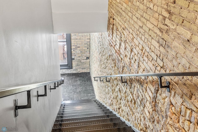 staircase featuring brick wall and hardwood / wood-style flooring