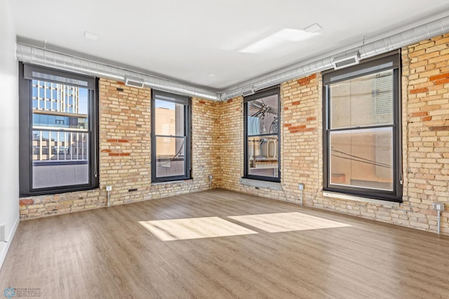 spare room with hardwood / wood-style floors and brick wall