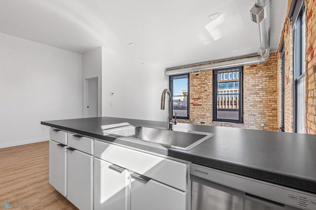 kitchen featuring dishwasher, sink, brick wall, light hardwood / wood-style floors, and white cabinets