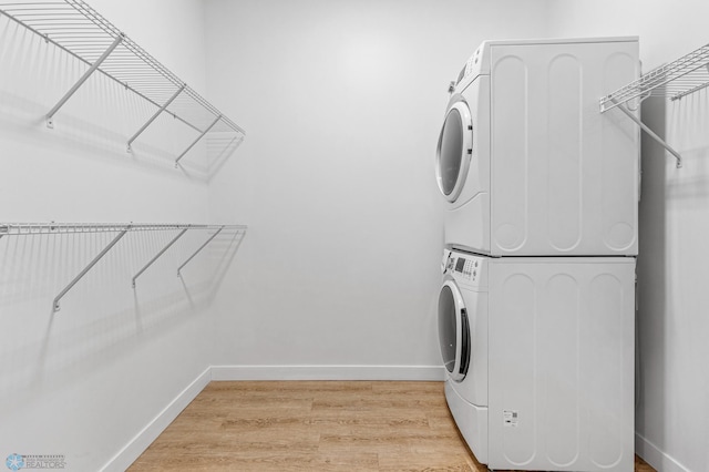 laundry room with light hardwood / wood-style floors and stacked washer / dryer