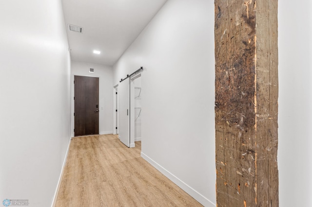 corridor with a barn door and light wood-type flooring