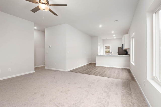 unfurnished living room with ceiling fan and light carpet