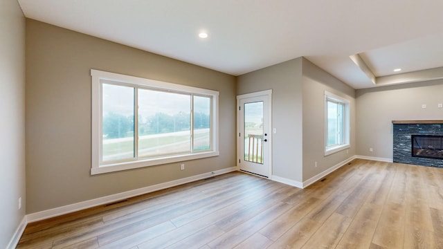 unfurnished living room featuring a stone fireplace and light hardwood / wood-style flooring