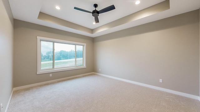 carpeted spare room with ceiling fan and a raised ceiling