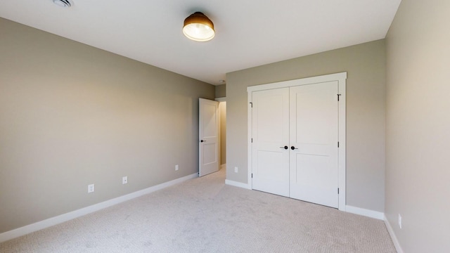 unfurnished bedroom with a closet and light carpet