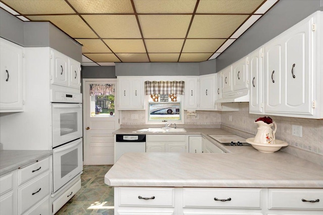 kitchen featuring a paneled ceiling and white cabinets