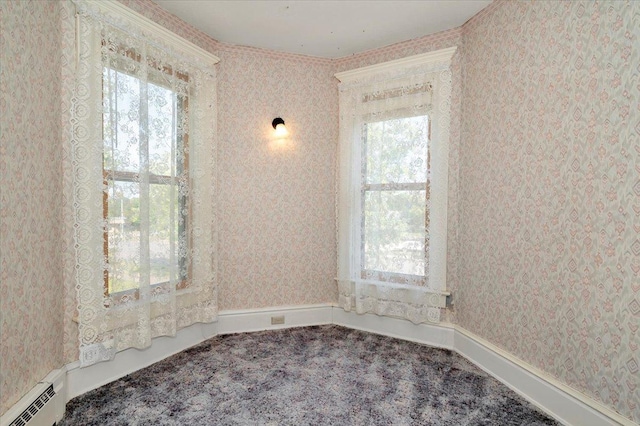 carpeted spare room featuring a baseboard heating unit and a healthy amount of sunlight