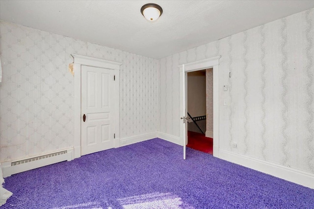 empty room with a baseboard heating unit, carpet floors, and a textured ceiling