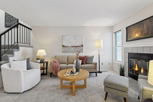 living room featuring light colored carpet, a textured ceiling, and a tiled fireplace