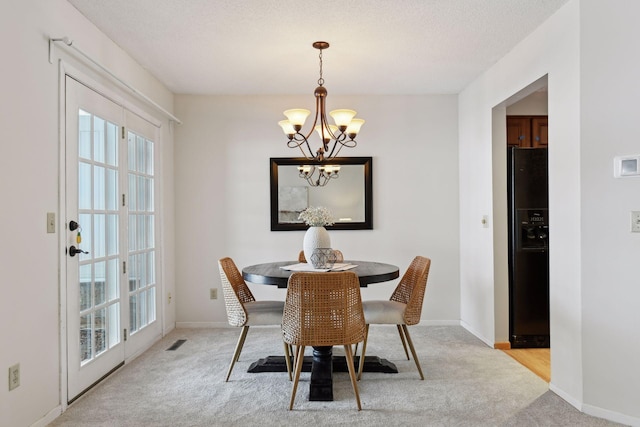 carpeted dining room featuring a textured ceiling and a chandelier