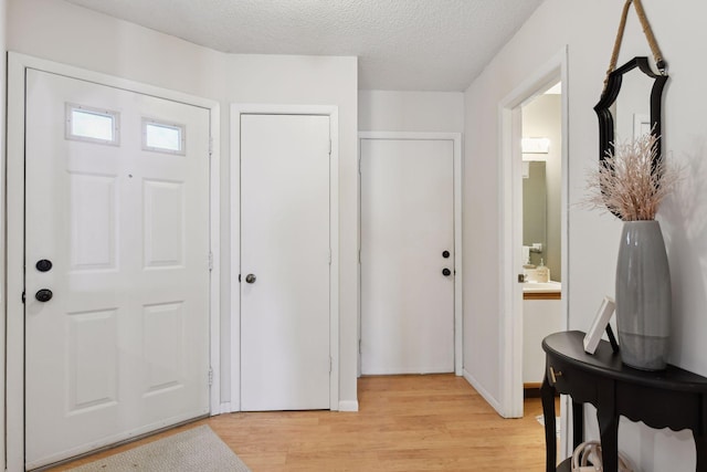 entryway with a textured ceiling and light hardwood / wood-style flooring