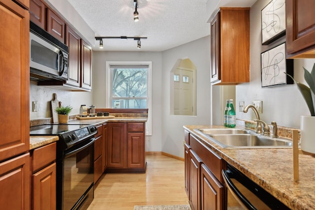 kitchen with black appliances, sink, light hardwood / wood-style flooring, a textured ceiling, and rail lighting