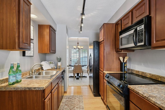 kitchen featuring light hardwood / wood-style floors, black appliances, sink, track lighting, and a chandelier