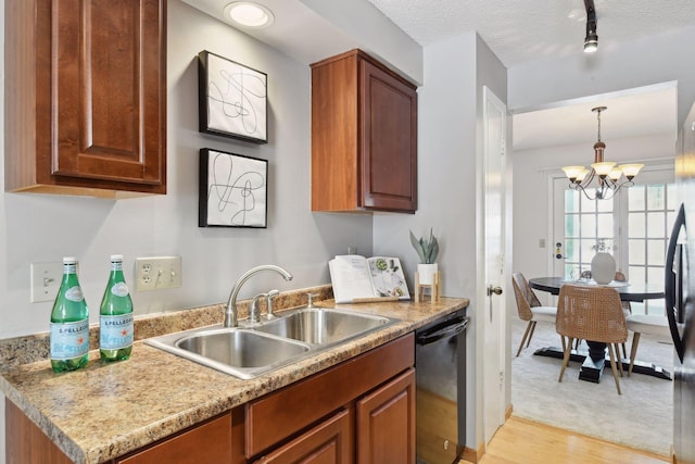 kitchen featuring light hardwood / wood-style floors, stainless steel dishwasher, sink, a chandelier, and rail lighting