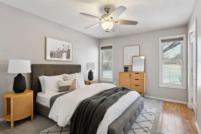 bedroom with ceiling fan, a textured ceiling, and light hardwood / wood-style flooring