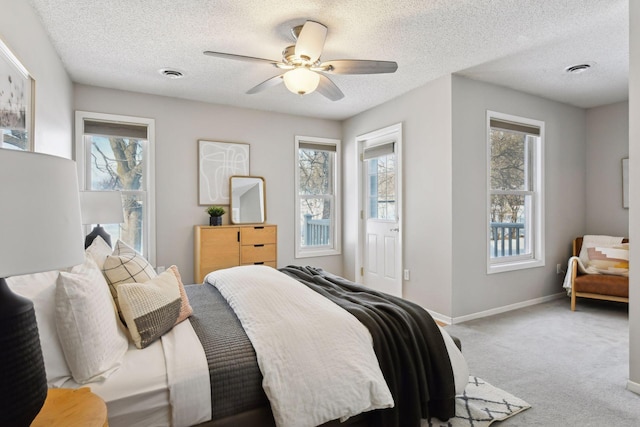 carpeted bedroom featuring a textured ceiling, ceiling fan, and multiple windows