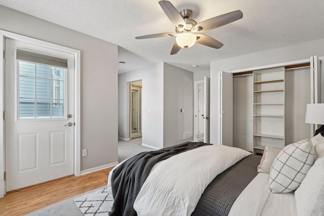 bedroom featuring a textured ceiling, ceiling fan, a closet, and light hardwood / wood-style flooring