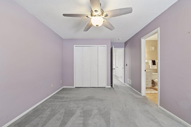 unfurnished bedroom with ceiling fan, light colored carpet, connected bathroom, and a textured ceiling