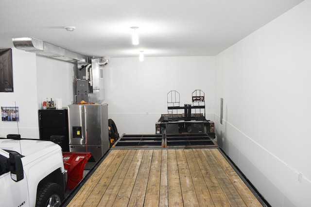 interior space with black refrigerator, stainless steel fridge with ice dispenser, hardwood / wood-style flooring, and heating unit