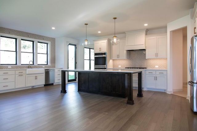 kitchen featuring decorative light fixtures, white cabinetry, stainless steel appliances, a center island, and dark hardwood / wood-style flooring