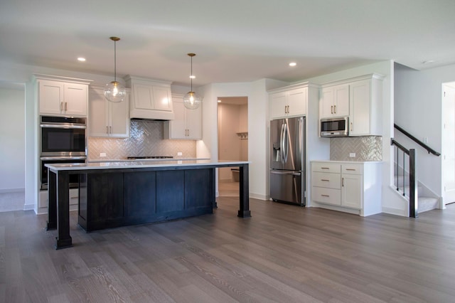 kitchen with appliances with stainless steel finishes, dark wood-type flooring, decorative light fixtures, and white cabinetry