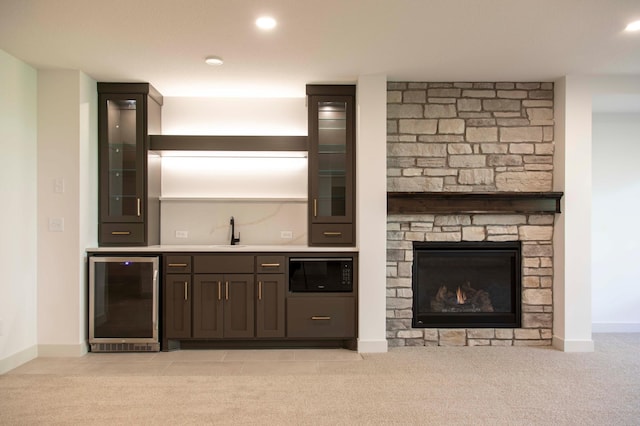 bar with dark brown cabinets, black microwave, wine cooler, and light colored carpet