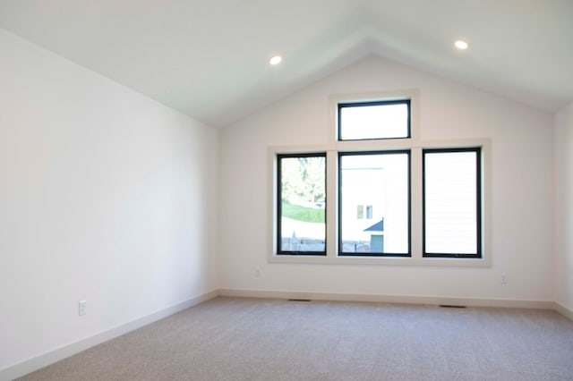 carpeted empty room featuring vaulted ceiling