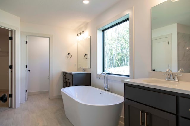 bathroom with wood-type flooring, a bath, and vanity