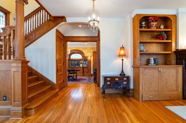 foyer with ornamental molding, a chandelier, and light wood-type flooring