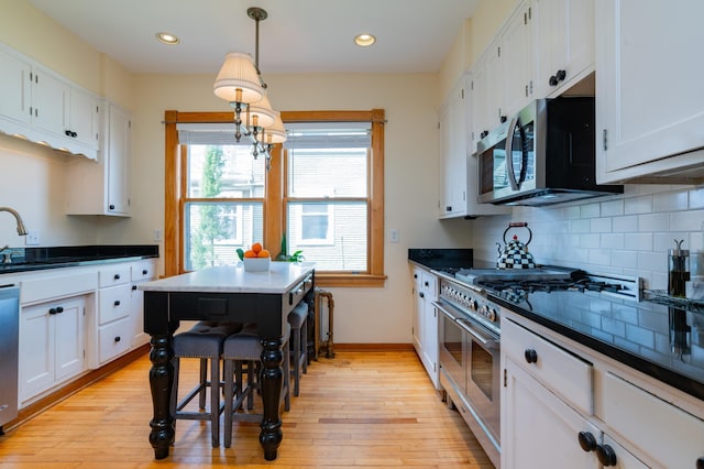 kitchen with light wood-type flooring, pendant lighting, white cabinetry, and stainless steel appliances