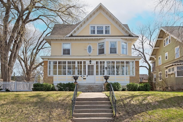 victorian-style house featuring a front lawn and a sunroom