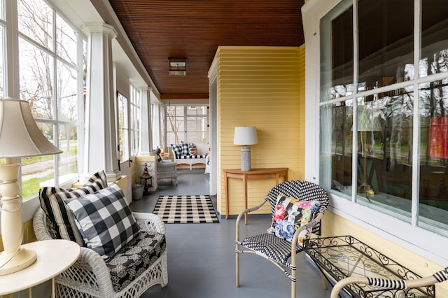 sunroom / solarium featuring decorative columns, a healthy amount of sunlight, and wooden ceiling