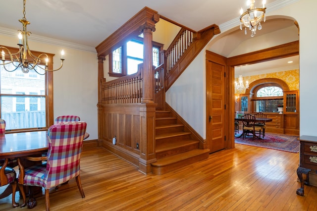 dining area with wood-type flooring, a wealth of natural light, crown molding, and an inviting chandelier