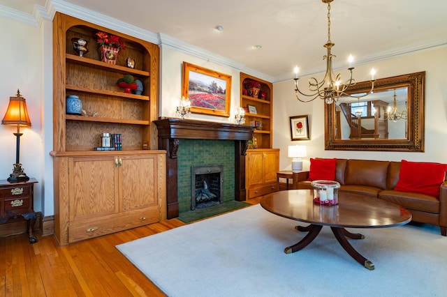 living room featuring a brick fireplace, built in features, crown molding, and light wood-type flooring