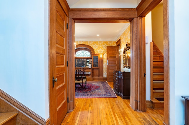 corridor with light hardwood / wood-style floors and ornamental molding